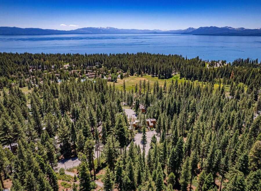 Nestled amidst a dense pine forest, this property offers a serene retreat with stunning views of a vast blue lake and distant snow-capped mountains.