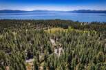 Nestled amidst a dense pine forest, this property offers a serene retreat with stunning views of a vast blue lake and distant snow-capped mountains.