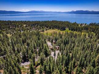 Nestled amidst a dense pine forest, this property offers a serene retreat with stunning views of a vast blue lake and distant snow-capped mountains.