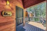 Welcome to this charming cabin-style home, featuring a rustic wooden exterior and a welcoming porch with a.