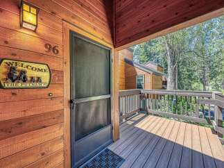 Welcome to this charming cabin-style home, featuring a rustic wooden exterior and a welcoming porch with a.