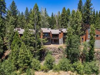 Nestled amidst towering pine trees, this stunning multi-level home offers a unique architectural design with warm wood exteriors and expansive balconies.