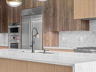 Experience luxury in this modern kitchen, featuring a sleek stainless steel Sub-Zero refrigerator and double ovens.