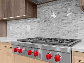 Experience culinary excellence in this modern kitchen, featuring a professional-grade Wolf range with iconic red knobs.