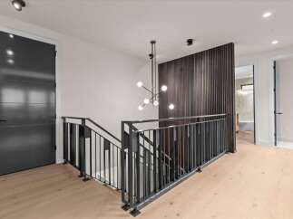 Experience modern luxury in this stunning home featuring a sleek dark gray door and a contemporary metal staircase railing.