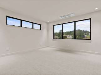Experience modern living in this spacious room featuring large, black-framed windows that flood the space with natural light.