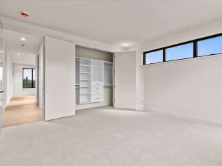 Step into this modern bedroom featuring a spacious walk-in closet with ample shelving and drawers.