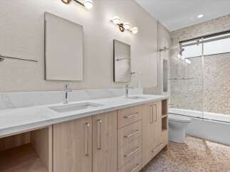 Experience modern luxury in this stunning bathroom featuring a double vanity with sleek faucets and a quartz countertop.