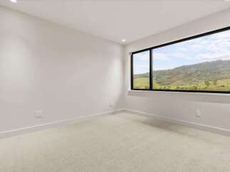 Experience breathtaking natural beauty from this spacious room, featuring a large picture window that frames a stunning landscape of rolling green hills and distant mountains.