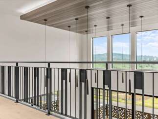 Experience modern luxury with this stunning interior featuring a sleek black metal railing overlooking a spacious open-concept living area.