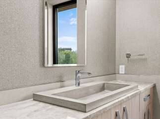 Experience modern luxury in this stunning bathroom featuring a unique concrete vessel sink and a sleek chrome faucet.