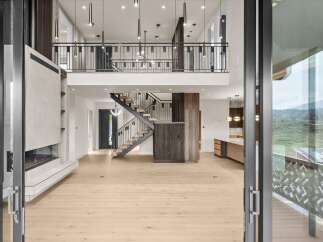 Experience modern luxury in this stunning open-concept living space, featuring a soaring double-height ceiling and a sleek, contemporary fireplace.