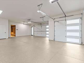 This spacious garage features a clean, epoxy-coated floor and ample lighting, perfect for vehicle storage or a workshop.