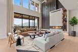 Experience luxurious living in this stunning modern living room, featuring a grand fireplace and expansive windows with breathtaking mountain views.