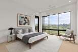 Experience modern luxury in this stunning bedroom featuring a king-sized bed, complemented by a large abstract artwork and expansive windows offering breathtaking views.