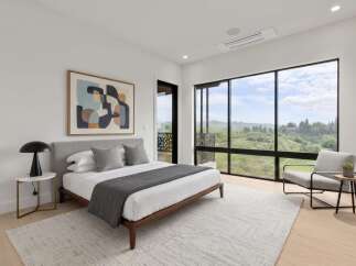 Experience modern luxury in this stunning bedroom featuring a king-sized bed, complemented by a large abstract artwork and expansive windows offering breathtaking views.