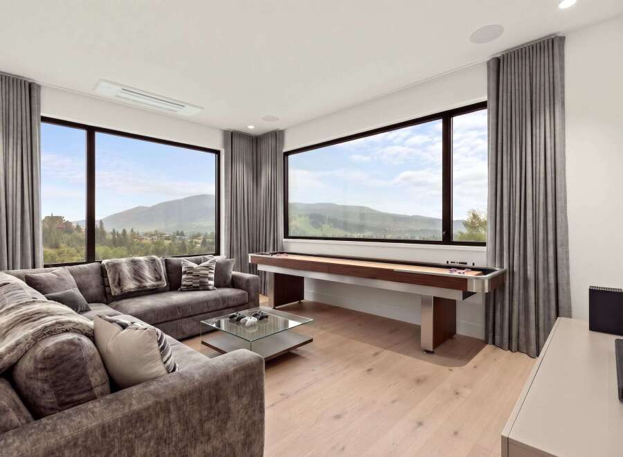 Experience breathtaking mountain views from this modern living room, featuring a plush sectional sofa and a stylish glass coffee table.