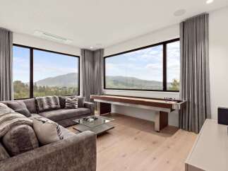 Experience breathtaking mountain views from this modern living room, featuring a plush sectional sofa and a stylish glass coffee table.