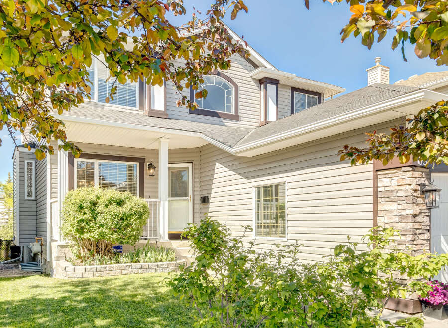 Charming two-story home featuring a welcoming front porch with a white column and a classic lantern.