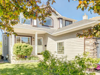 Charming two-story home featuring a welcoming front porch with a white column and a classic lantern.