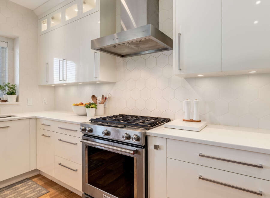 Experience modern elegance in this stunning kitchen, featuring sleek white cabinetry and a chic hexagonal tile backsplash.