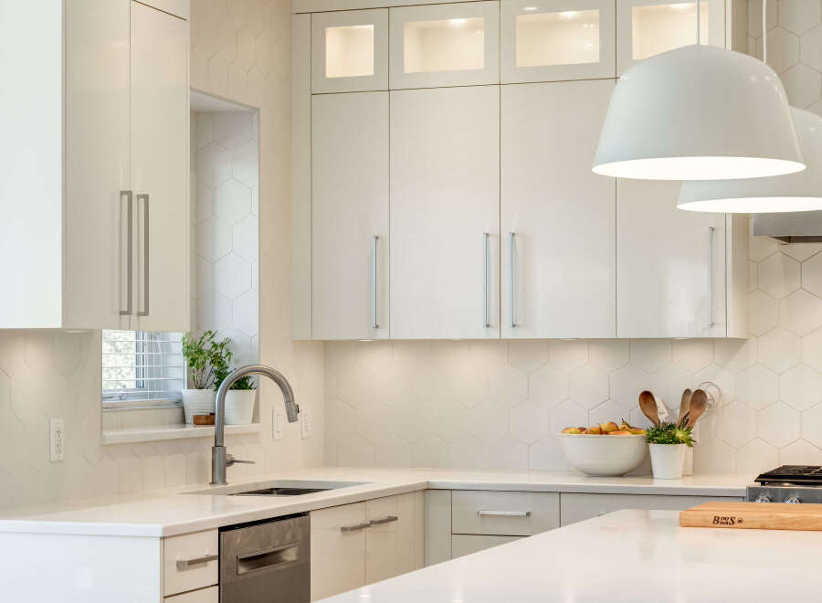 Experience modern elegance in this stunning kitchen, featuring sleek white cabinetry and a chic hexagonal tile backsplash.