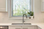 This modern kitchen features a sleek stainless steel faucet over a double basin sink, complemented by a hexagonal tile backsplash.