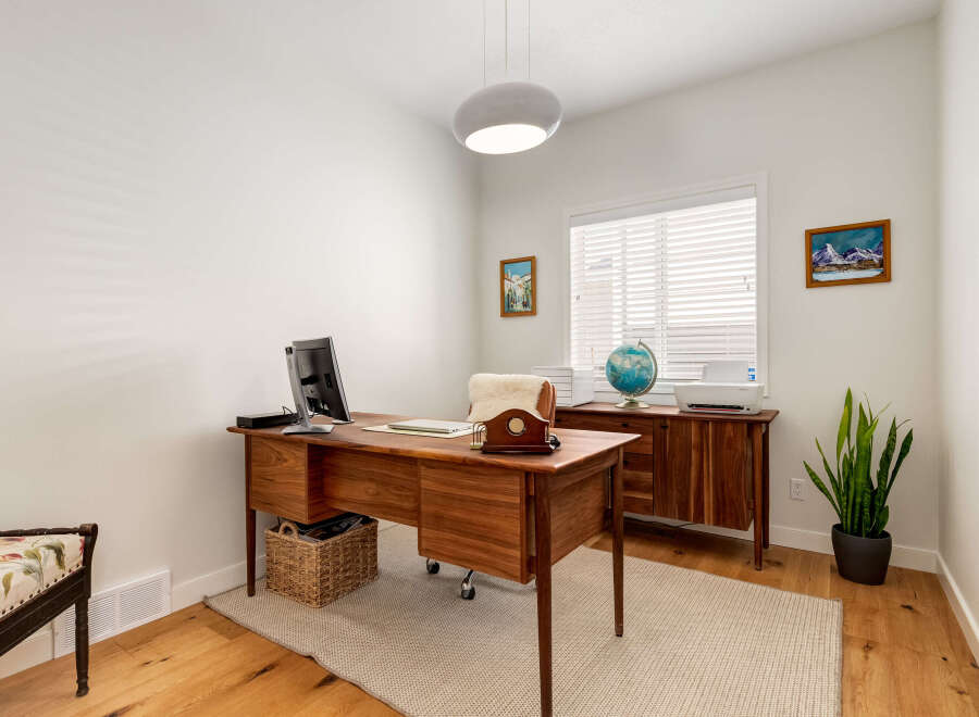 This home office features a beautiful wooden desk with a computer and laptop, perfect for productivity.