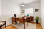 This home office features a beautiful wooden desk with a computer and laptop, perfect for productivity.