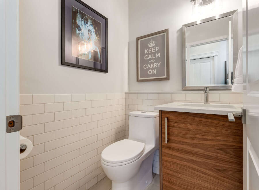 This modern bathroom features a sleek vanity with a rich wood grain finish, complemented by a white subway tile backsplash.