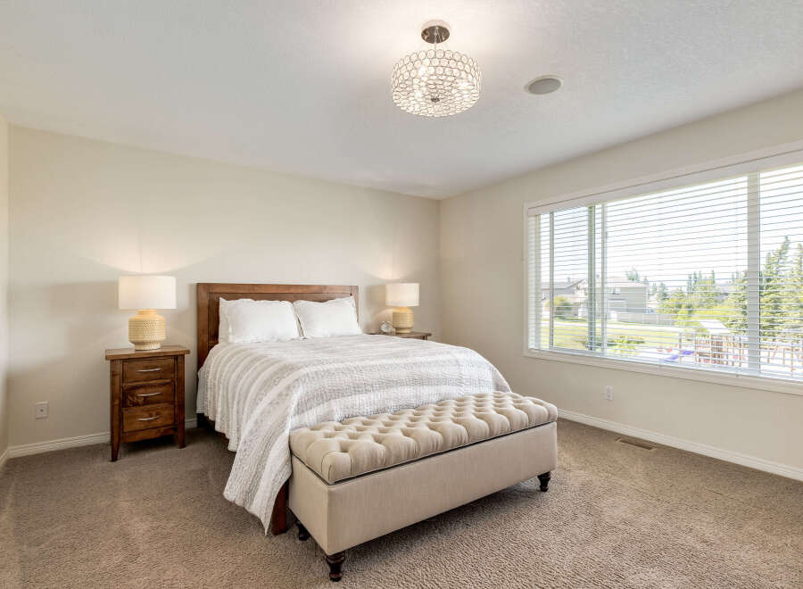 This inviting bedroom features a comfortable queen-size bed with crisp white linens and a striped quilt, complemented by two matching bedside tables with lamps.