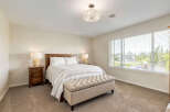 This inviting bedroom features a comfortable queen-size bed with crisp white linens and a striped quilt, complemented by two matching bedside tables with lamps.