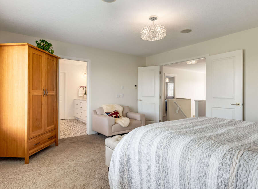 Step into this inviting bedroom featuring a spacious wooden wardrobe and a cozy armchair with a Union Jack pillow.