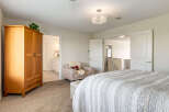 Step into this inviting bedroom featuring a spacious wooden wardrobe and a cozy armchair with a Union Jack pillow.