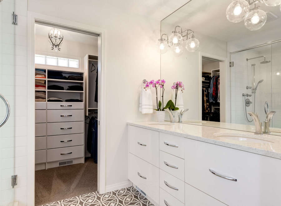 This modern bathroom features a spacious walk-in closet with ample storage, including shelves and drawers.