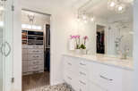 This modern bathroom features a spacious walk-in closet with ample storage, including shelves and drawers.