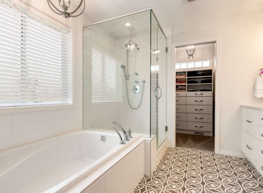 Indulge in luxury with this stunning bathroom featuring a deep soaking tub and a separate glass-enclosed shower with multiple shower heads.