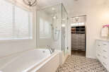 Indulge in luxury with this stunning bathroom featuring a deep soaking tub and a separate glass-enclosed shower with multiple shower heads.