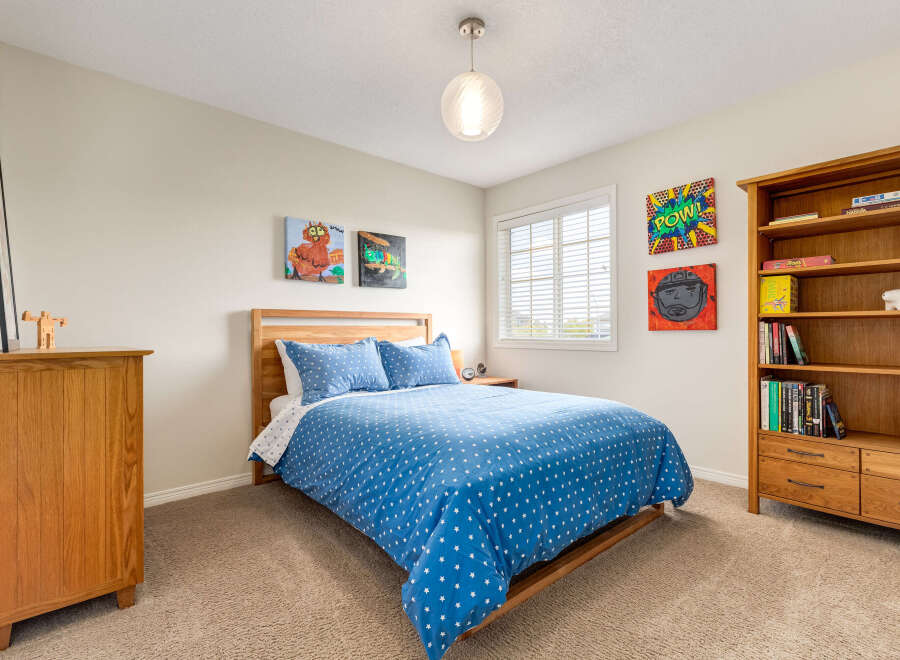 This charming bedroom features a cozy wooden bed with a playful blue star-patterned duvet, complemented by a matching pillow.