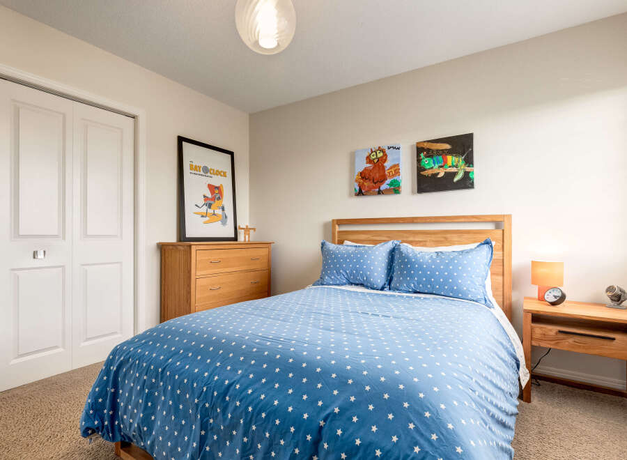 This charming bedroom features a cozy queen-size bed adorned with a playful blue star-patterned duvet and matching pillows.
