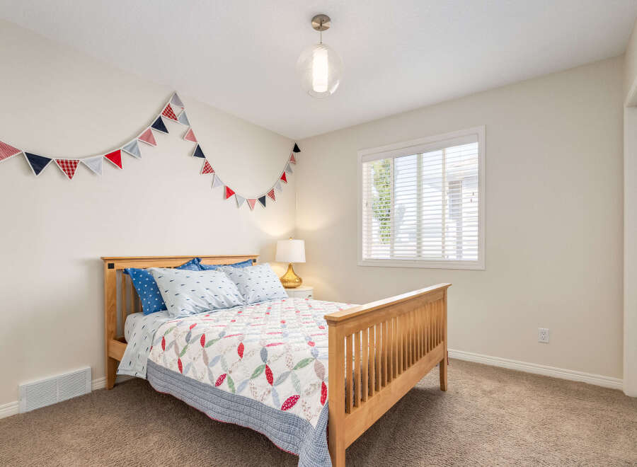 This charming bedroom features a cozy wooden bed adorned with nautical-themed bedding and a festive triangle garland.
