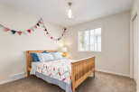 This charming bedroom features a cozy wooden bed adorned with nautical-themed bedding and a festive triangle garland.