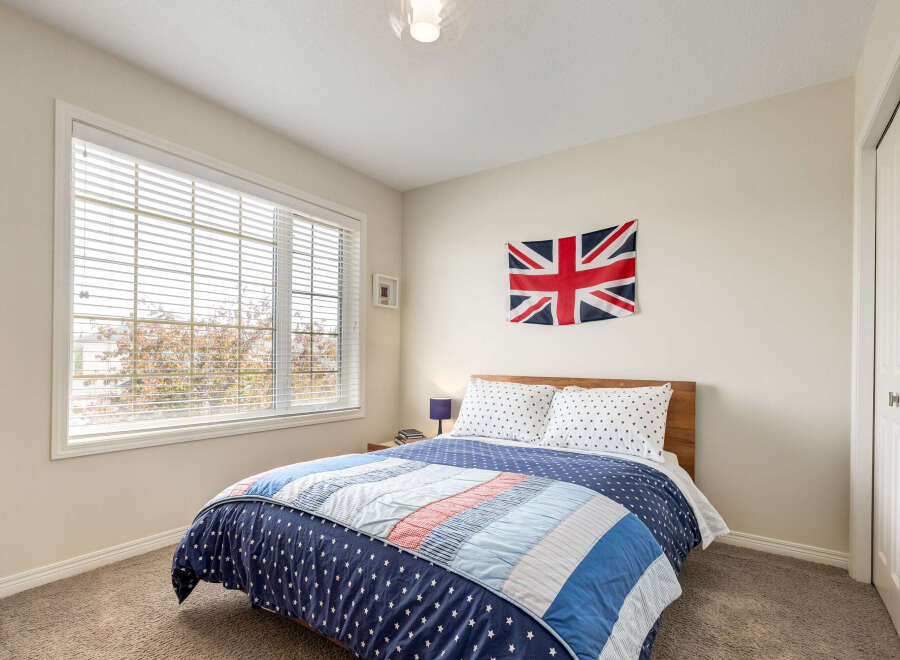 This charming bedroom features a cozy queen-size bed adorned with patriotic-themed bedding, including a Union Jack flag displayed prominently on the wall.