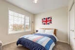 This charming bedroom features a cozy queen-size bed adorned with patriotic-themed bedding, including a Union Jack flag displayed prominently on the wall.