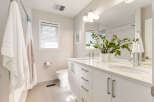This modern bathroom features a spacious double vanity with sleek white cabinetry and a marble countertop, complemented by two vessel sinks and chrome faucets.