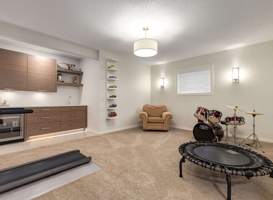 This versatile basement space offers a dedicated home gym area with a treadmill and a mini-trampoline, perfect for workouts.