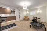 This versatile basement space offers a dedicated home gym area with a treadmill and a mini-trampoline, perfect for workouts.