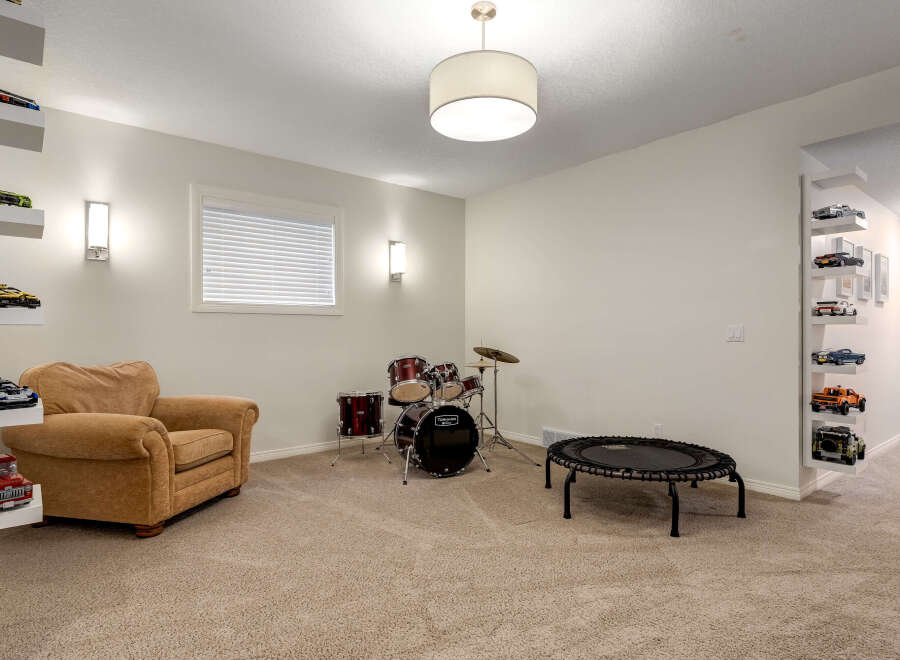 This versatile room offers a perfect blend of entertainment and relaxation, featuring a comfortable armchair, a drum set for musical exploration, and a mini-trampoline for active fun.
