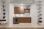 This modern home bar features sleek, dark wood cabinetry and a built-in wine fridge, perfect for entertaining.
