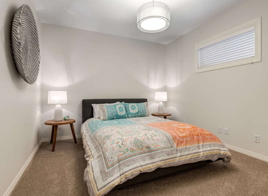 This inviting bedroom features a comfortable queen-size bed adorned with a vibrant, patterned duvet and decorative pillows.